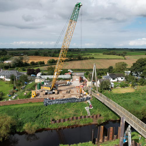 Drone shot of crane lifting piles into place 