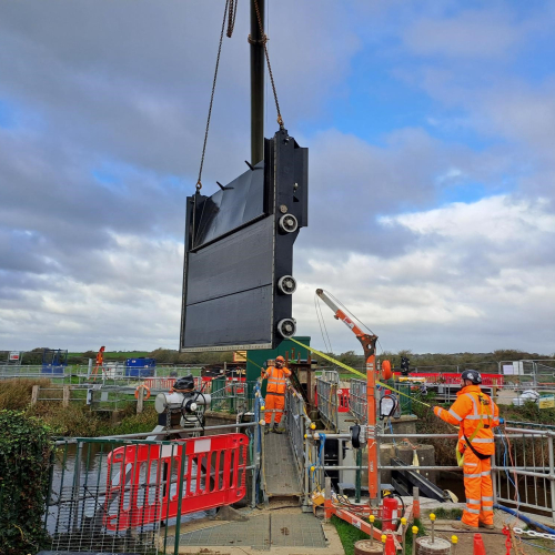 Large flood gate being lifted into position on construction site