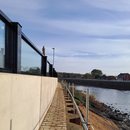 Glass flood panels a top a concrete wall by a river