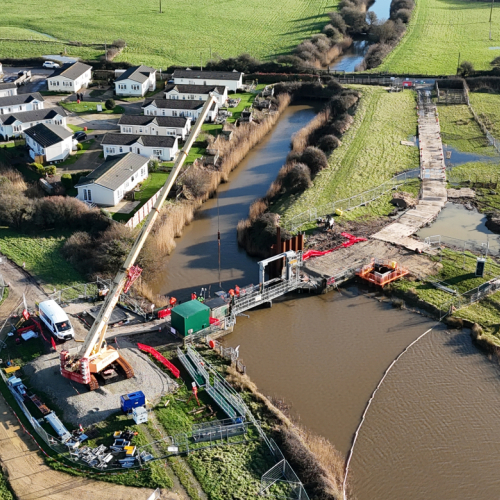 A river with a crane on a bridge.