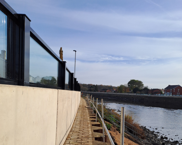 Glass flood panels a top a concrete wall by a river