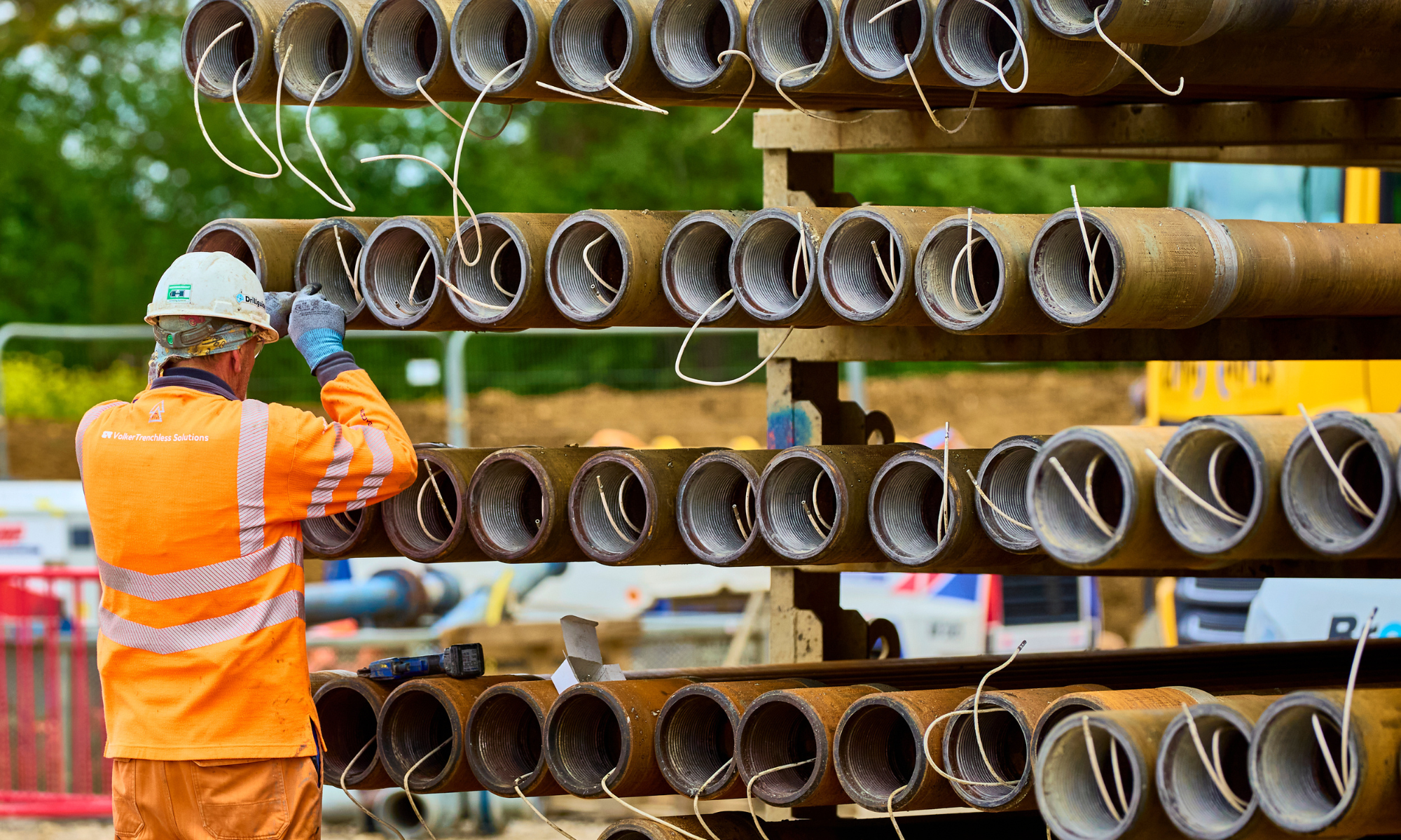 Man in orange PPE organising pipe casings
